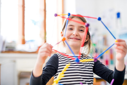 Portrait of schoolgirl using educational tool, learning geometry during class, feeling accomplished. Student girl in classroom at the elementary school