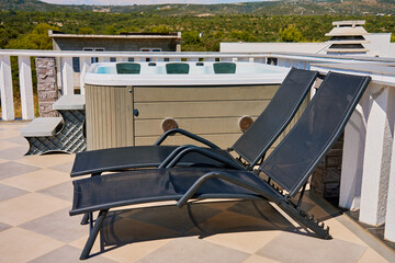 Sunny rooftop deck with hot tub and two black lounge chairs. Jacuzzi with beautiful natural view....