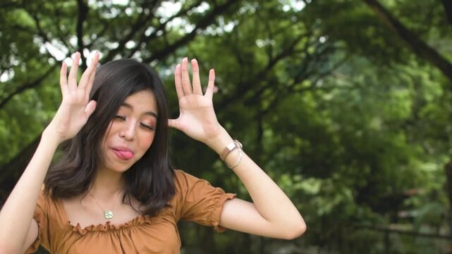 A young woman is laughing and making fun of someone for being clumsy. Outdoor park background. Slowed down 50 percent.