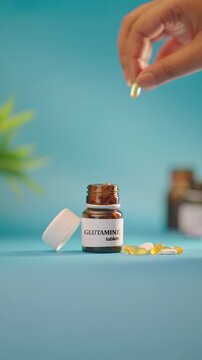 VERTICAL VIDEO OF HAND TAKING OUT GLUTAMINE TABLETS FROM MEDICINE BOTTLE