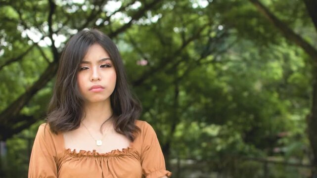 A grouchy young woman refuses to look after not hearing what she wants. Feeling upset at someone. Outdoor park scene. Slowed down 50 percent.