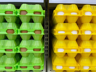 Plastic egg containers in a supermarket, close-up. Yellow and green packages with chicken eggs. 