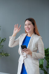Fototapeta premium Confident and positive Asian online businesswoman using smartphone at table to relax with mobile application, use chat, video call, business and marketing contact. Online excellent profits.