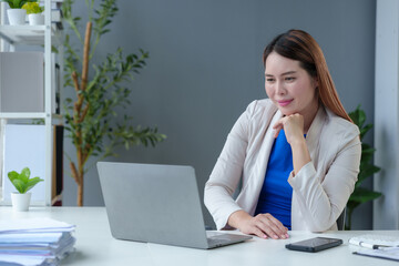 Asian businesswoman sitting in office stressed and fatigued from overwork on financial matters on office desk.