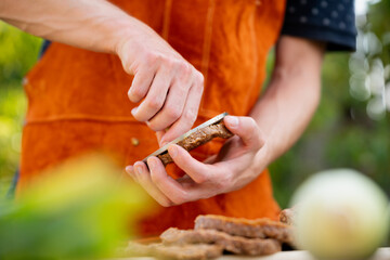 Man in apron preparing meat for hamburgers, standing outdoors. Using burger patty press to shape groud meat.