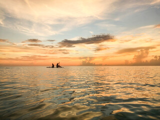 Silhouette young sisters on paddle board sunset Gulf of Mexico