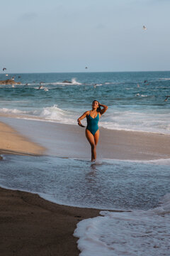 Woman walking down beach holding shell