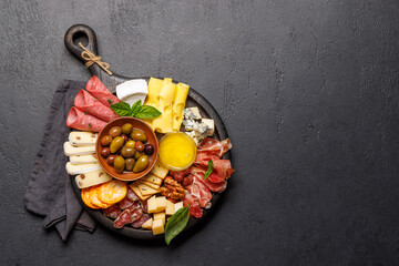 A selection of various cheeses and meats arranged on a wooden board