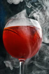 A refreshing Aperol Spritz cocktail in a wine glass with ice cubes and orange slices. The drink is...