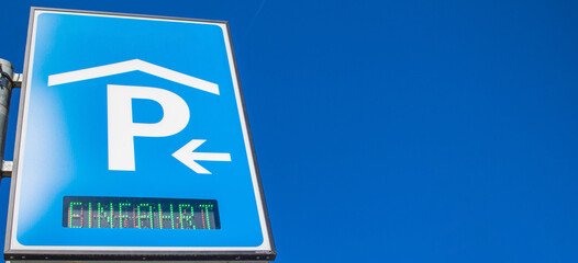 Hinweisschild für eine Parkhauseinfahrt vor blauem Himmel mit Freiraum für eigenen Text auf der...