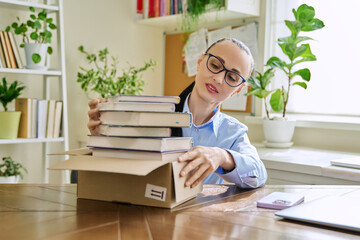 Woman with new books unpacked from cardboard box