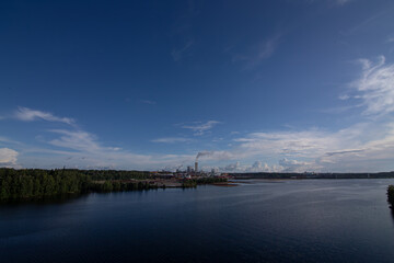 Industrial landscape with lake, stormy sky and factory during golden hour. Industry harmonized with nature concept