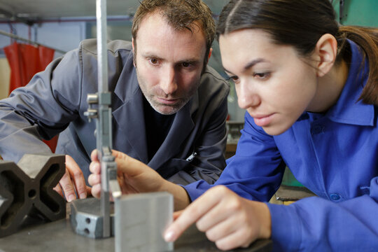 metal worker woman operating drilling machine - Powered by Adobe
