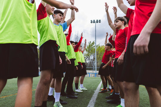 Soccer teams with arms raised standing in front of each other