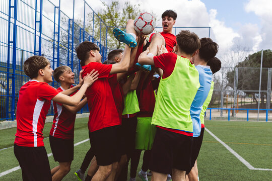 Soccer team cheering teammate and celebrating victory at field