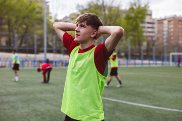 Soccer player standing with hands behind head on field