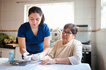 Nurse assists elderly woman with blood glucose test at home