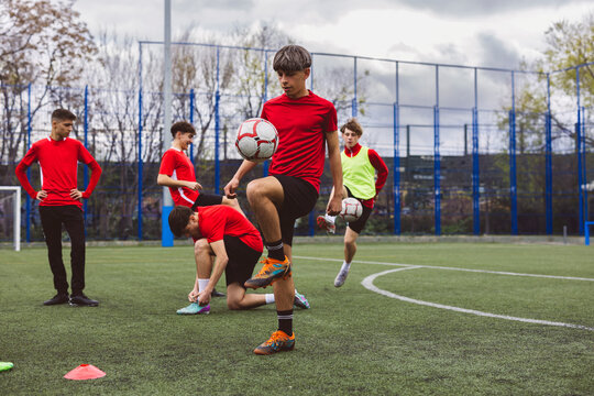 Soccer players playing with sports balls on field
