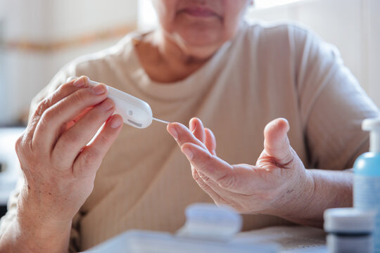 Elderly woman measuring blood sugar to monitor hypoglycemia