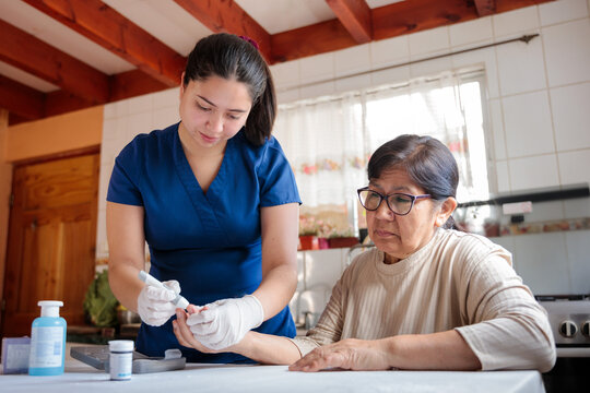 Nurse assisting elderly woman with blood glucose test