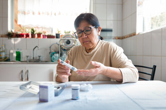 Senior woman monitoring blood sugar level at home