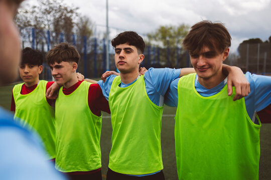 Happy soccer team standing with arms around on field