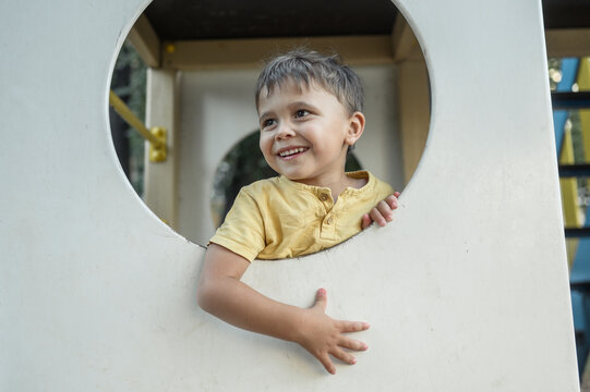 Smiling boy looking through circle of playing equipment at playground