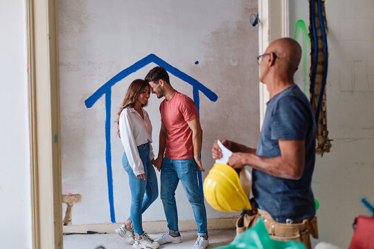 Construction worker with man embracing woman at site