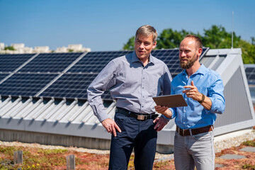 Two executives discussing business strategies while enjoying the view of solar panels on the rooftop of their company