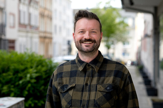Smiling businessman in flannel shirt at street