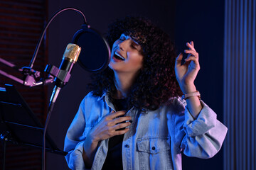 Vocalist singing into microphone in professional record studio