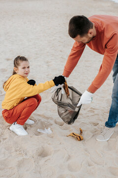 Father and daughter collecting trash on beach