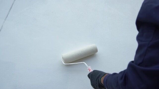 Close up of painter hand holding brush painting white wall. Home painting and decorating concept. House for sale or real estate.