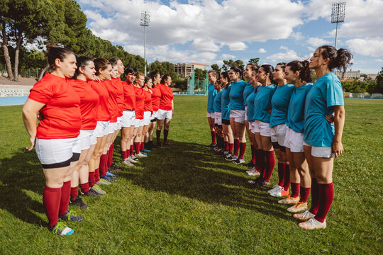 Rugby teams standing in row under cloudy sky at field