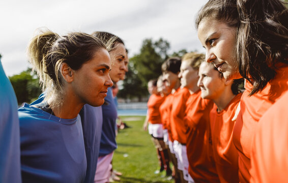 Smiling rugby teams standing face to face at field