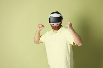 Smiling man using virtual reality headset on pale green background