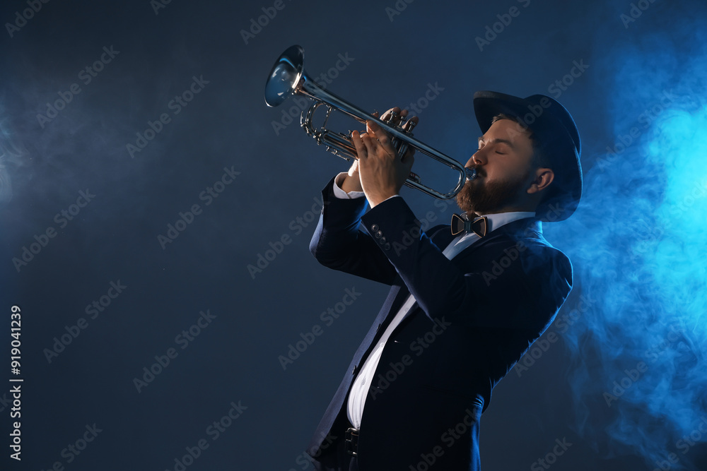 Wall mural Professional musician playing trumpet on dark background in blue lights and smoke. Space for text