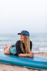 Pensive woman sitting on SUP board on beach