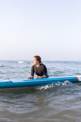 Woman swimming on paddleboard in sea