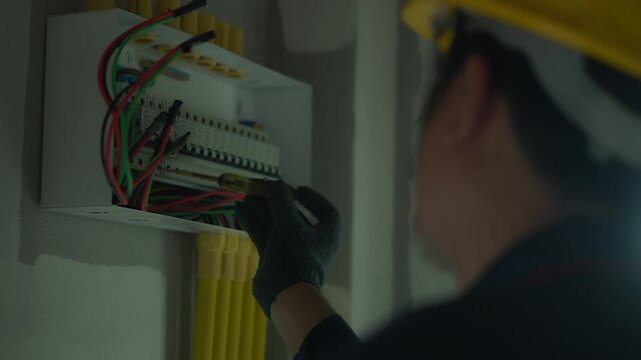 Electrician using electric screwdriver tester to check electric current in control box in home electrical installation and safety concept