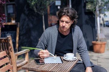 Businessman sitting and pretending to write with scallion near cafe