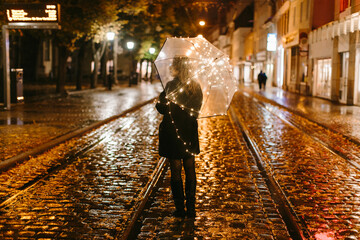 Woman with illuminated umbrella standing on street