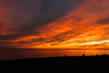 Traveler silhouettes contemplating sea from beach at night