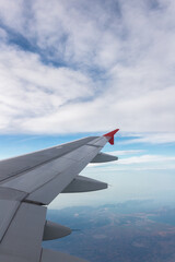Obraz premium Airplane flying under cloudy sky over ocean and land