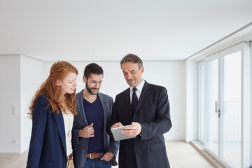 Real estate agent teaching couple to use automated system on tablet PC
