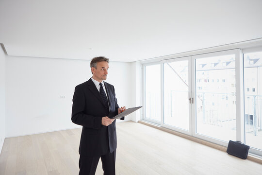 Real estate agent looking around with file in empty apartment