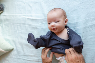 Crop dad dressing newborn on bed