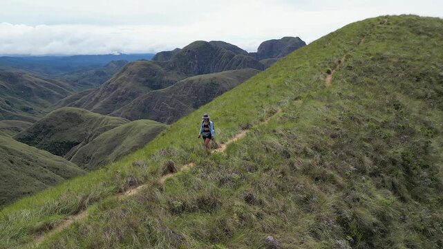 Female backpacker hikes down mtn ridge, Codo de los Andes in Bolivia