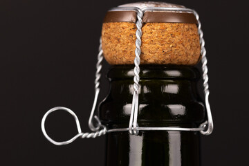 A detailed view of a champagne cork and metal foil on a black background, symbolizing New Year's Eve and festive celebrations.