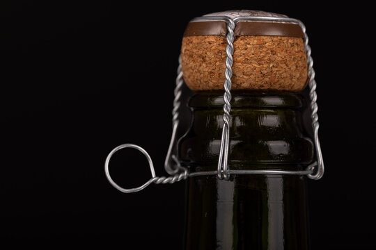 Detailed view of a champagne cork and wire on the right side against a black background, evoking a sense of holiday and New Year's celebration.